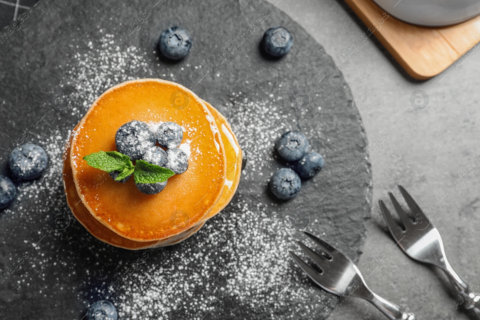 Photo of Tasty pancakes with berries on slate plate, top view