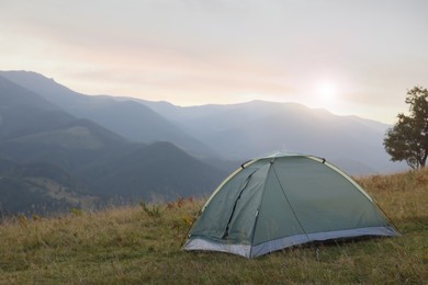 Photo of Grey camping tent in mountains at sunrise, space for text