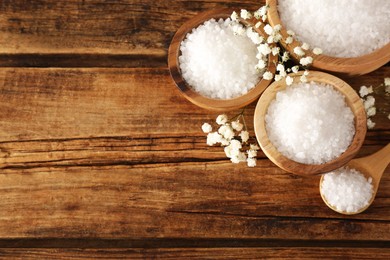 Photo of Aromatic sea salt and beautiful flowers on wooden table, flat lay. Space for text