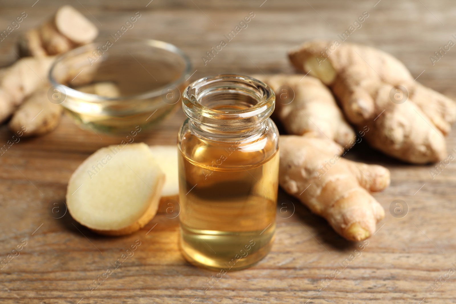 Photo of Ginger essential oil in bottle on wooden table