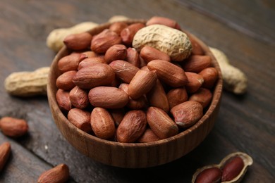 Fresh peanuts in bowl on wooden table, closeup