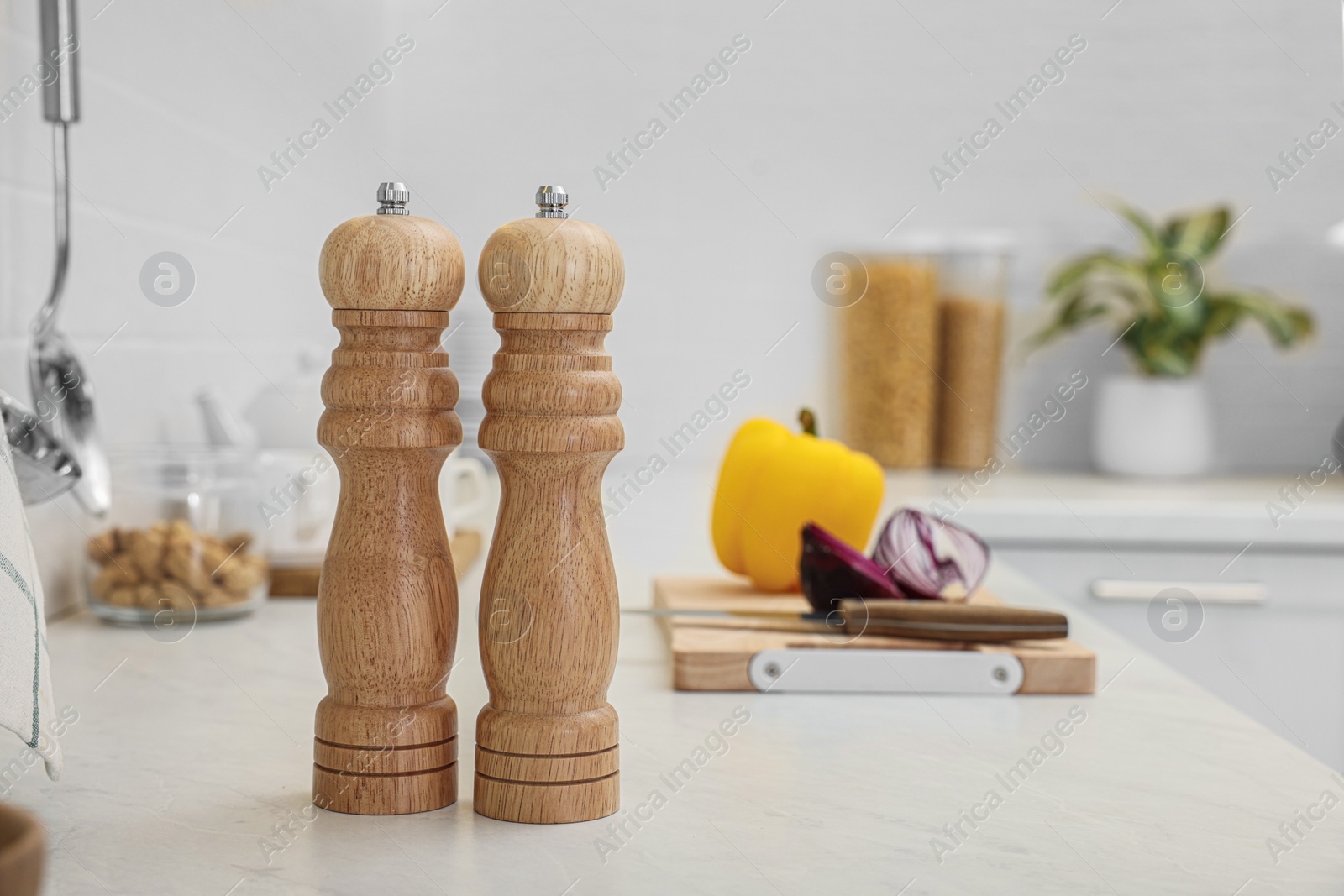 Photo of Wooden salt and pepper shakers on white countertop in kitchen, space for text