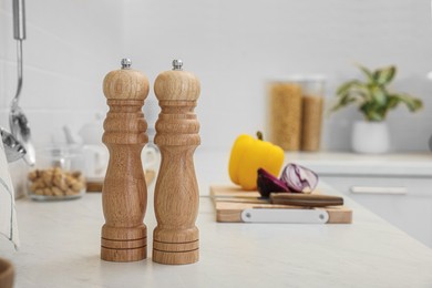 Photo of Wooden salt and pepper shakers on white countertop in kitchen, space for text