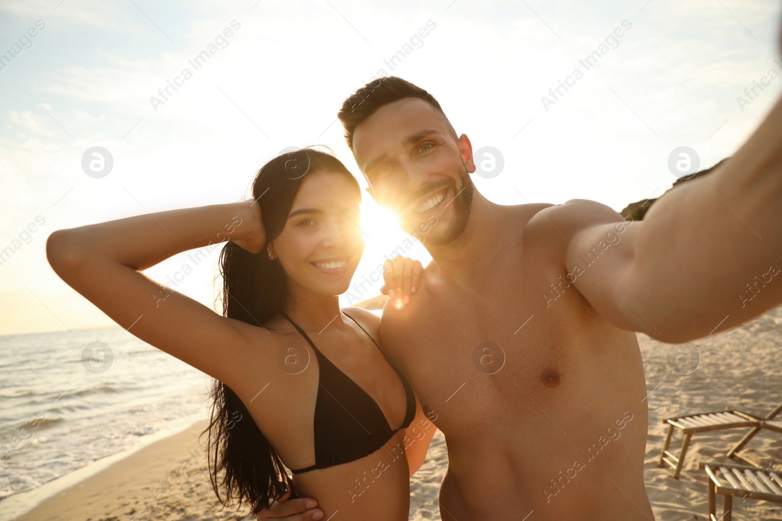 Photo of Happy young couple taking selfie on beach at sunset