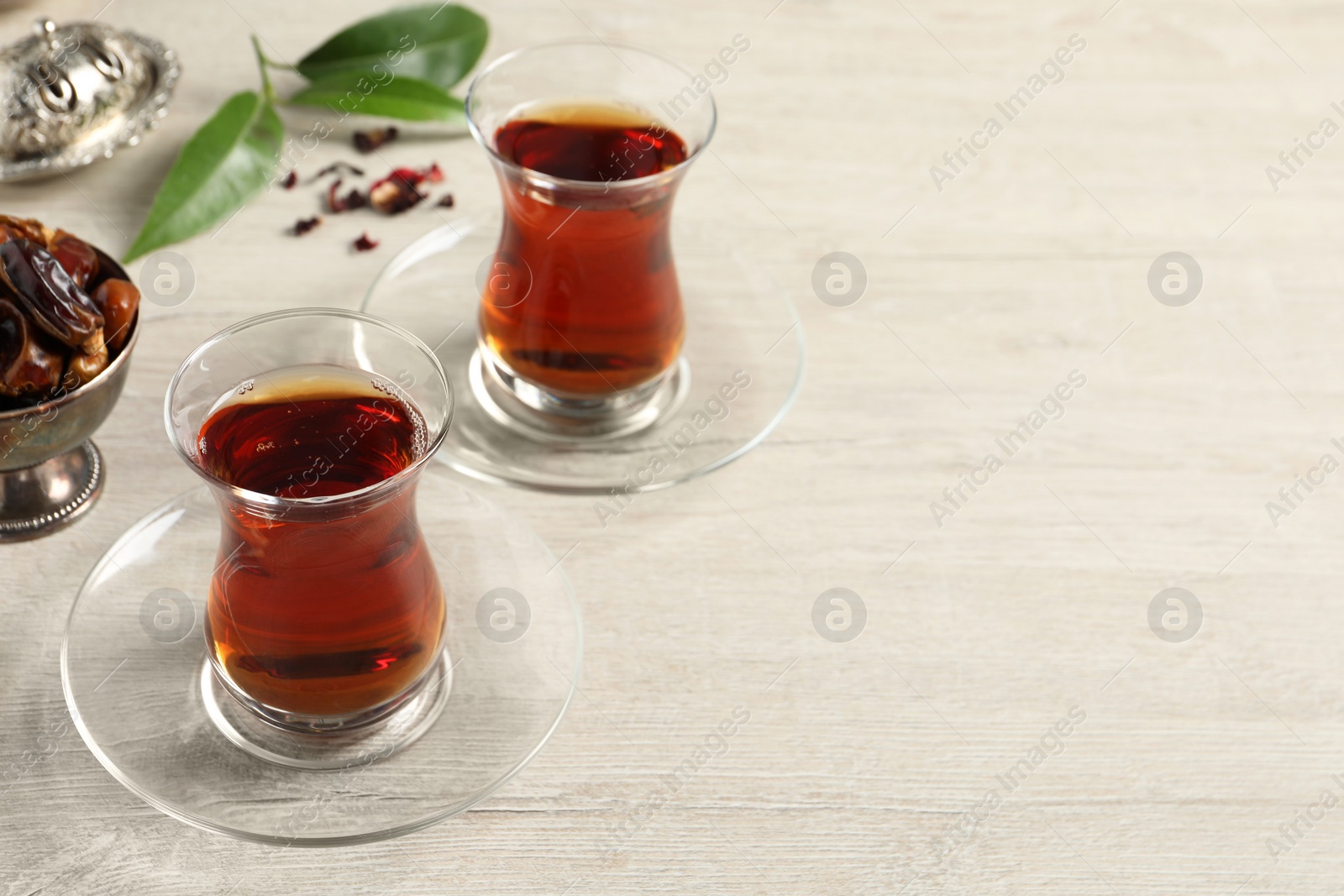 Photo of Glasses of tea and vintage tea set on wooden table, space for text