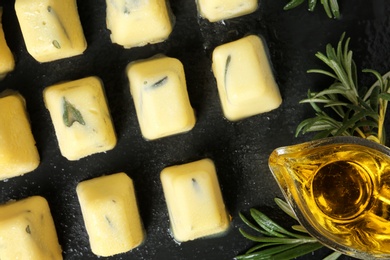 Flat lay composition with rosemary and olive oil ice cubes on dark background