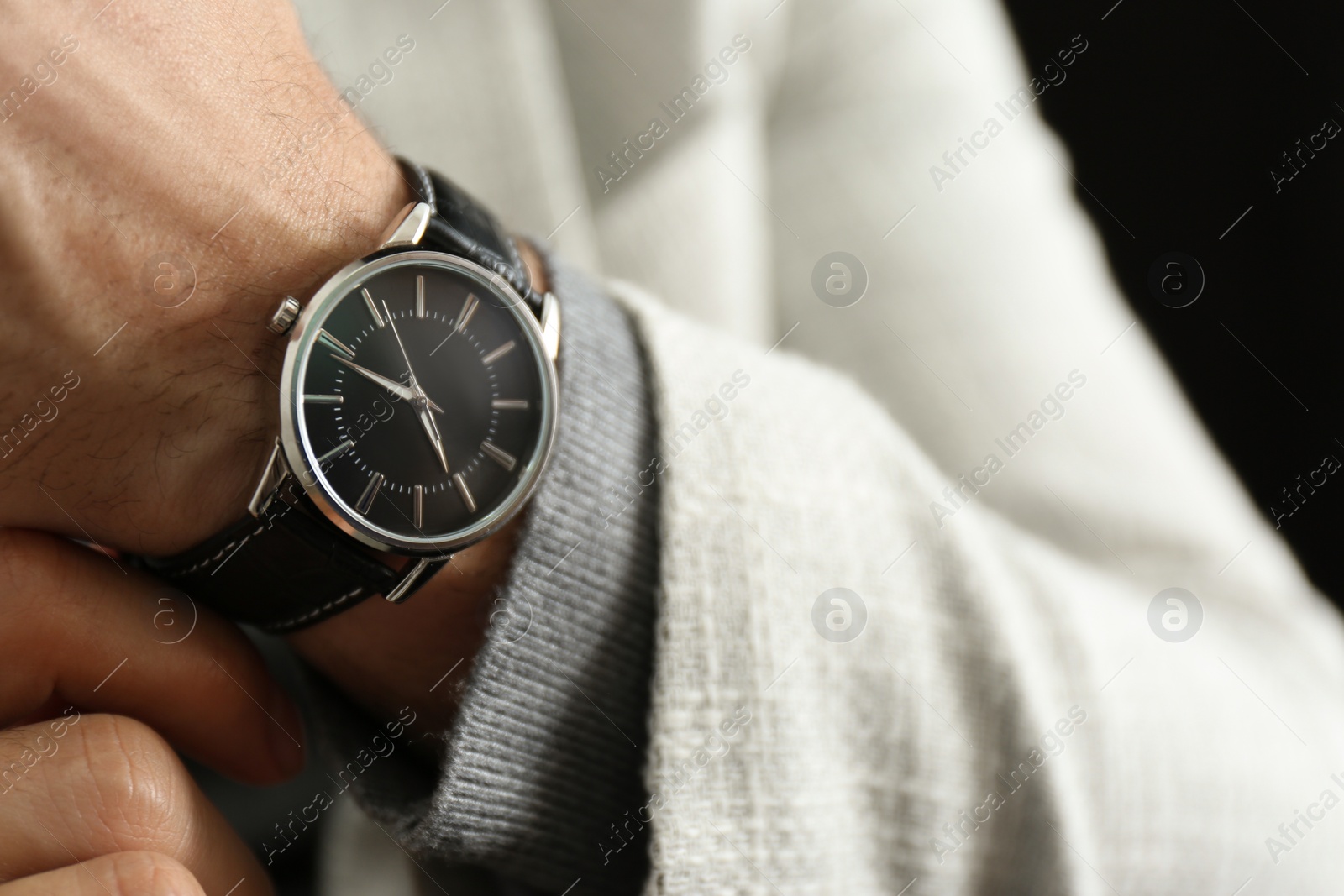 Photo of Businessman in jacket with luxury wrist watch on black background, closeup