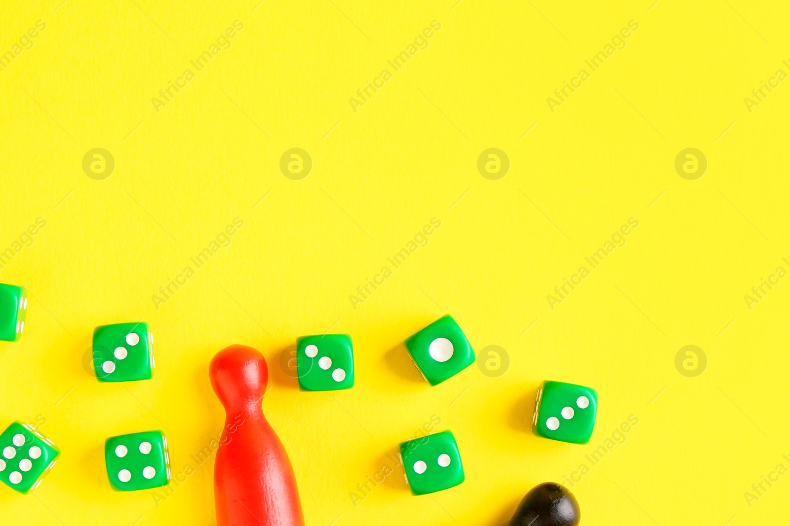 Photo of Many green dices and color game pieces on yellow background, flat lay