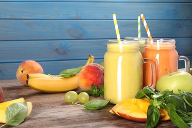 Photo of Mason jars of different tasty smoothies and fresh ingredients on wooden table. Space for text