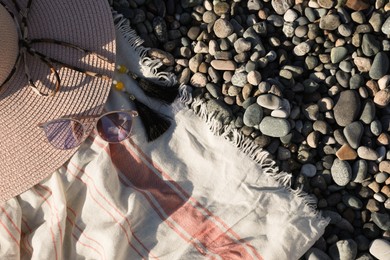 Photo of Beautiful hat with sunglasses and cloth on pebbles, flat lay. Space for text