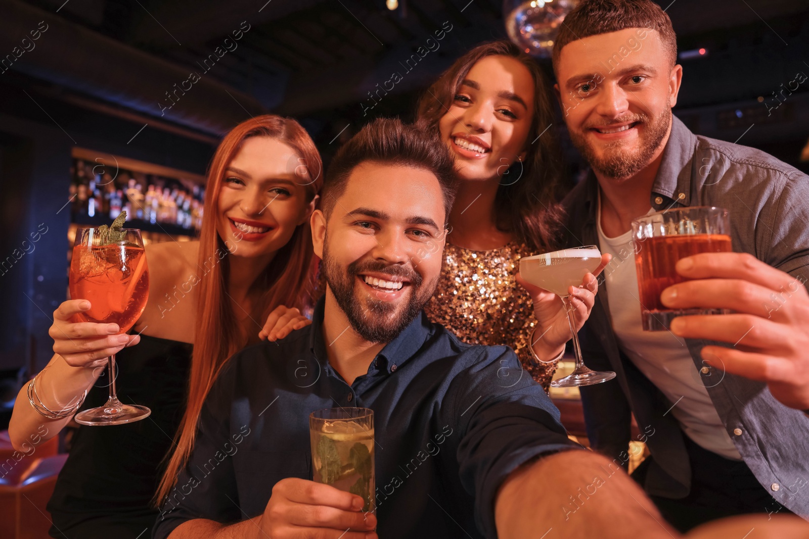 Photo of Happy friends with cocktails taking selfie together in bar