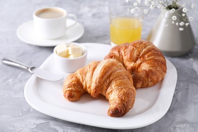 Photo of Tasty breakfast. Fresh croissants and butter on grey table, closeup