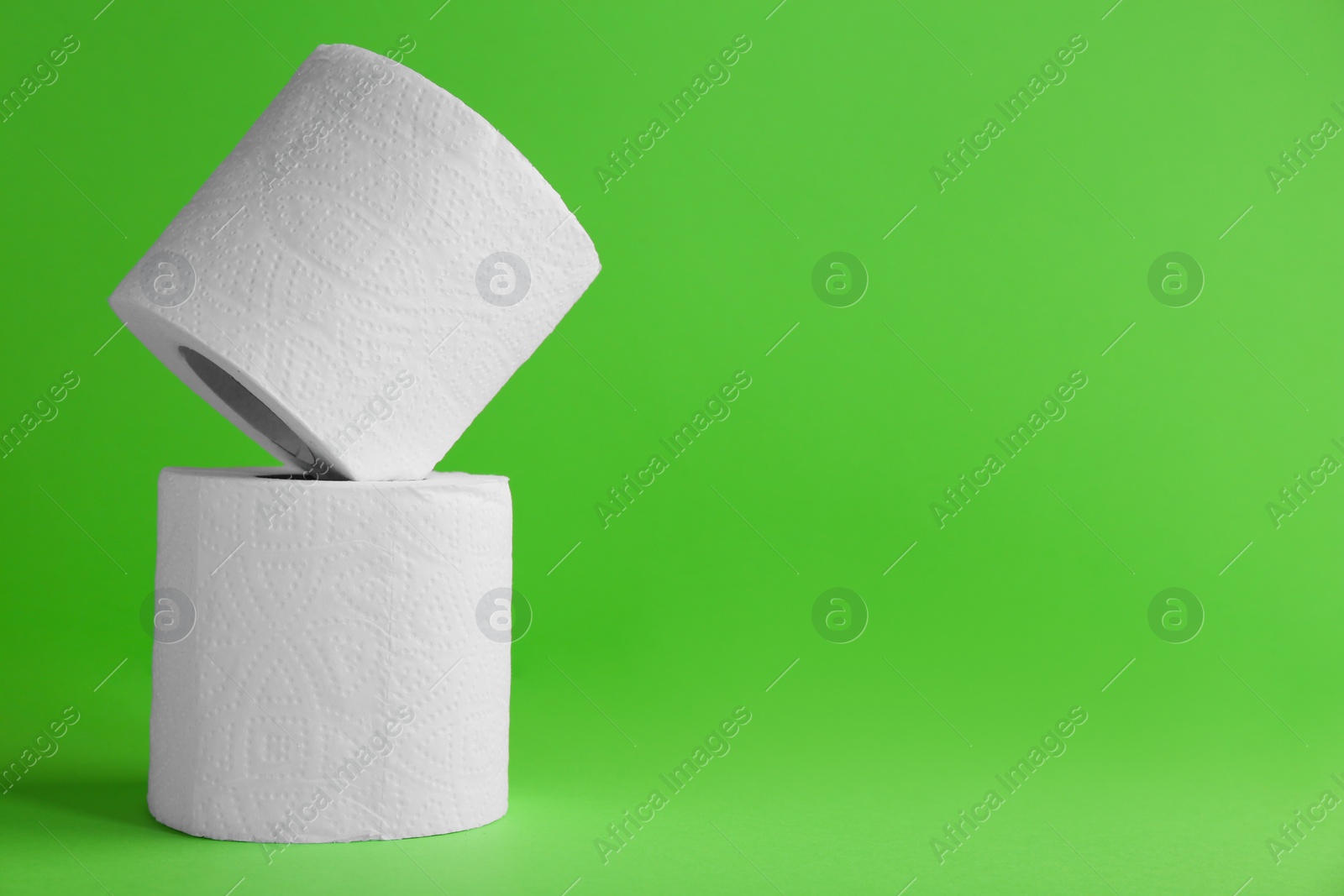 Photo of Soft toilet paper rolls on green background, closeup. Space for text