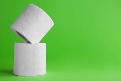 Photo of Soft toilet paper rolls on green background, closeup. Space for text