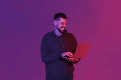 Image of Handsome man with laptop in neon lights