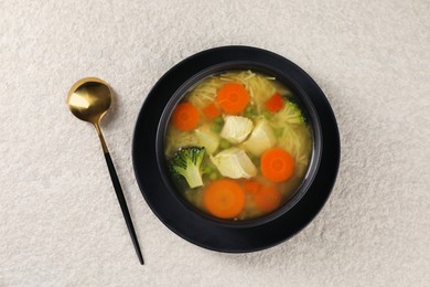 Photo of Tasty chicken soup with noodles and vegetables in bowl served on light textured table, top view