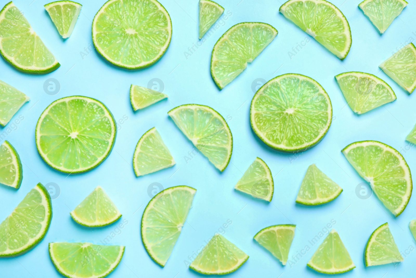 Photo of Juicy fresh lime slices on light blue background, flat lay