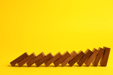 Falling wooden domino tiles on yellow background. Space for text