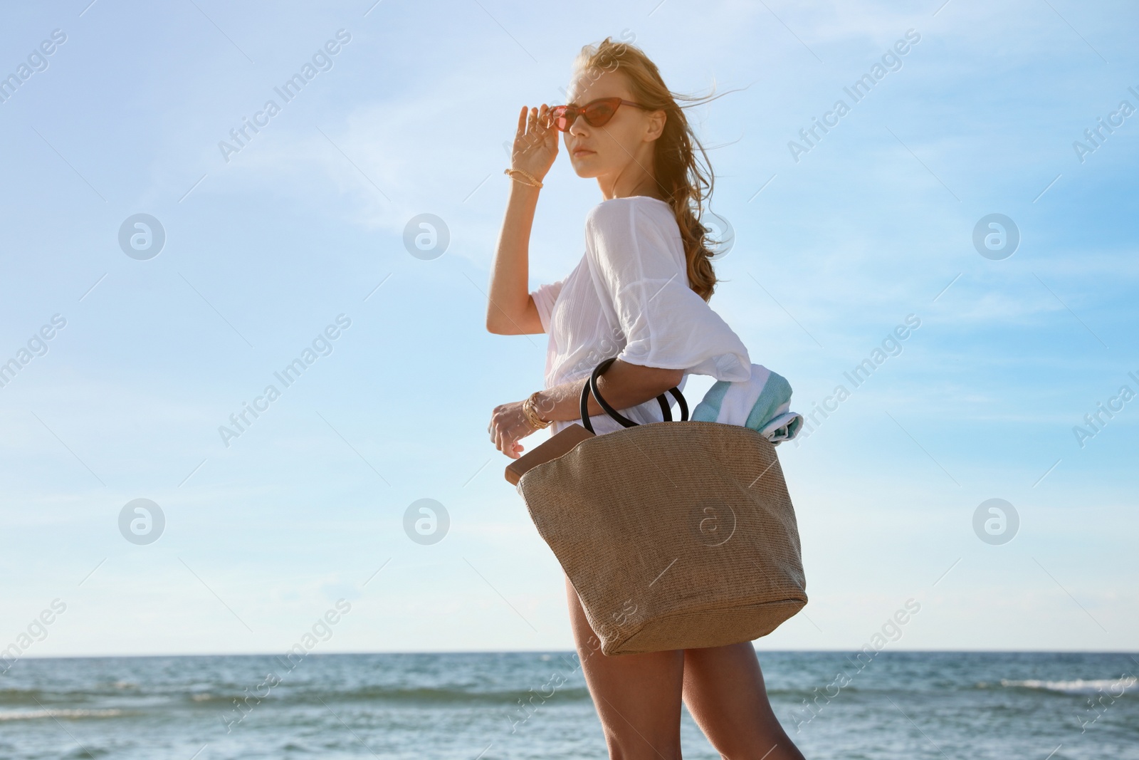 Photo of Beautiful woman carrying bag with beach towel near sea