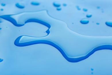 Drops of spilled water on blue background, closeup