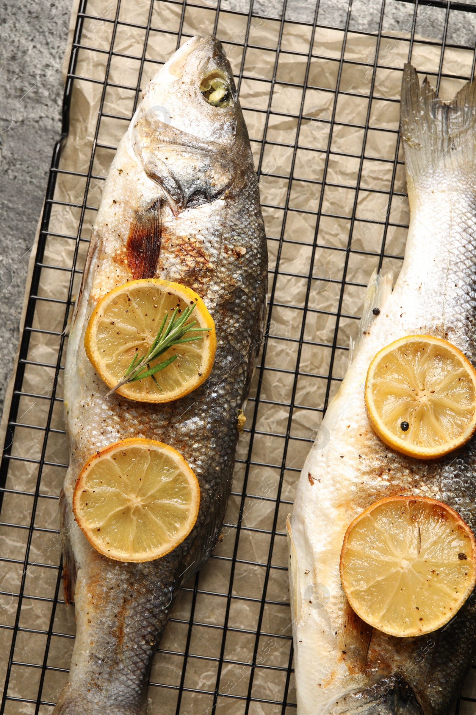 Photo of Baked fish with lemon on grey textured table, top view