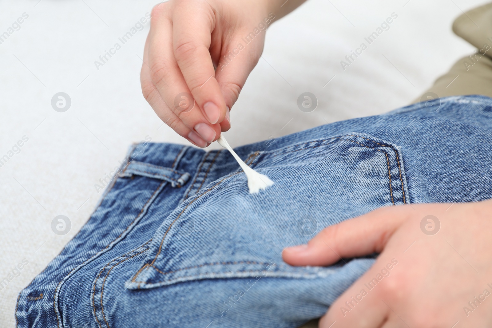 Photo of Woman removing chewing gum from jeans, closeup