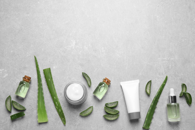 Flat lay composition with aloe vera and cosmetic products on grey background. Space for text