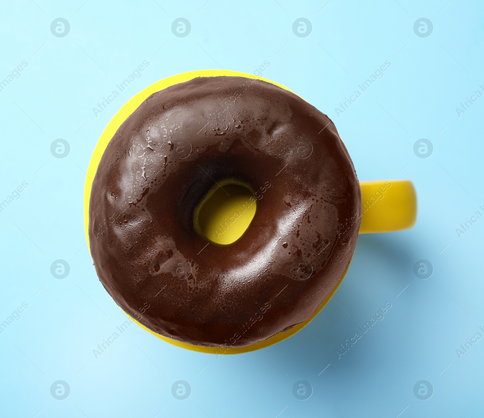 Photo of Cup of coffee made with donut on light blue background, top view