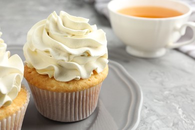 Photo of Tasty cupcakes with vanilla cream on grey table, closeup. Space for text