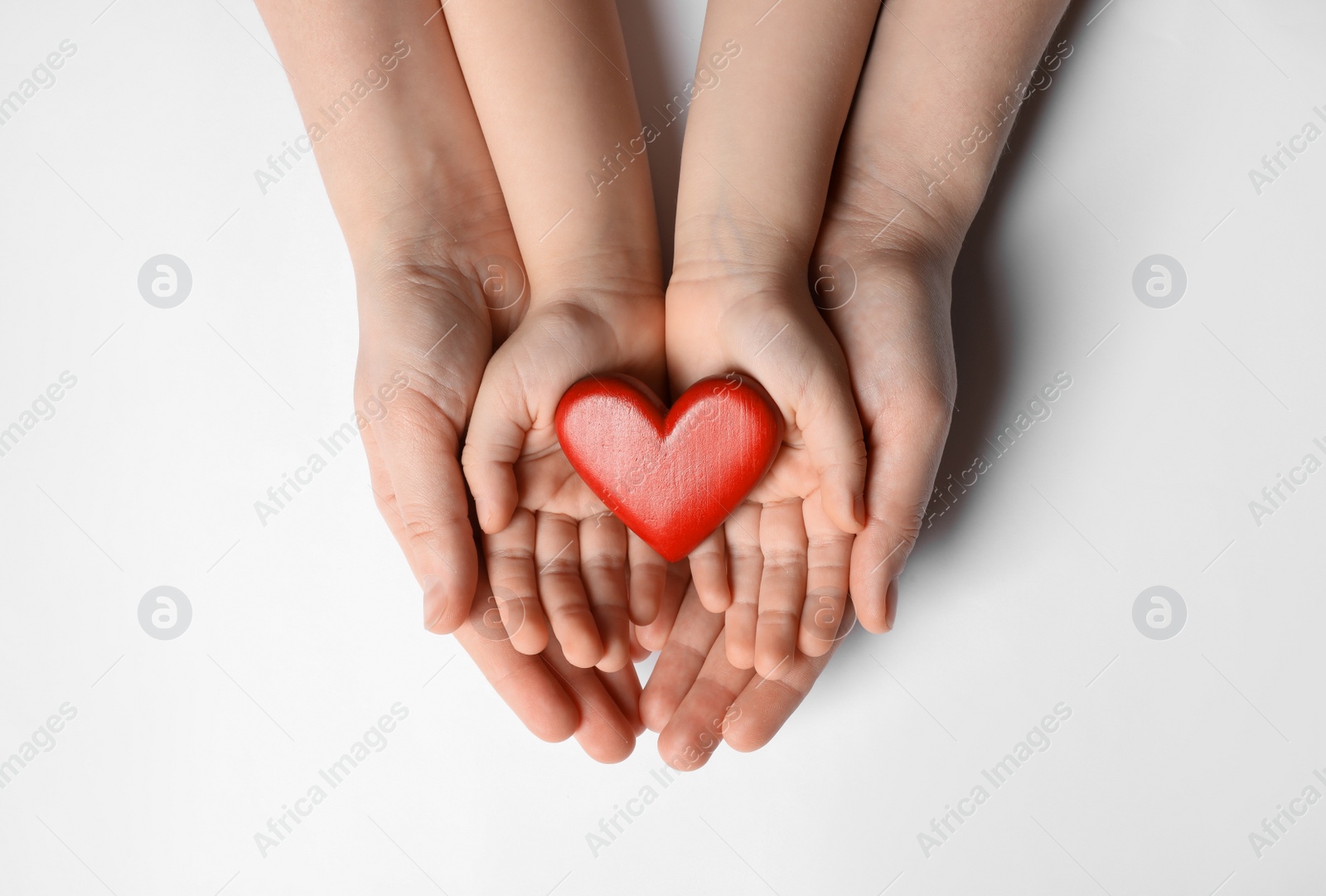 Photo of Woman and kid holding red heart in hands on white background, top view