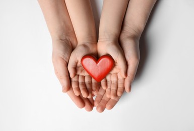 Photo of Woman and kid holding red heart in hands on white background, top view