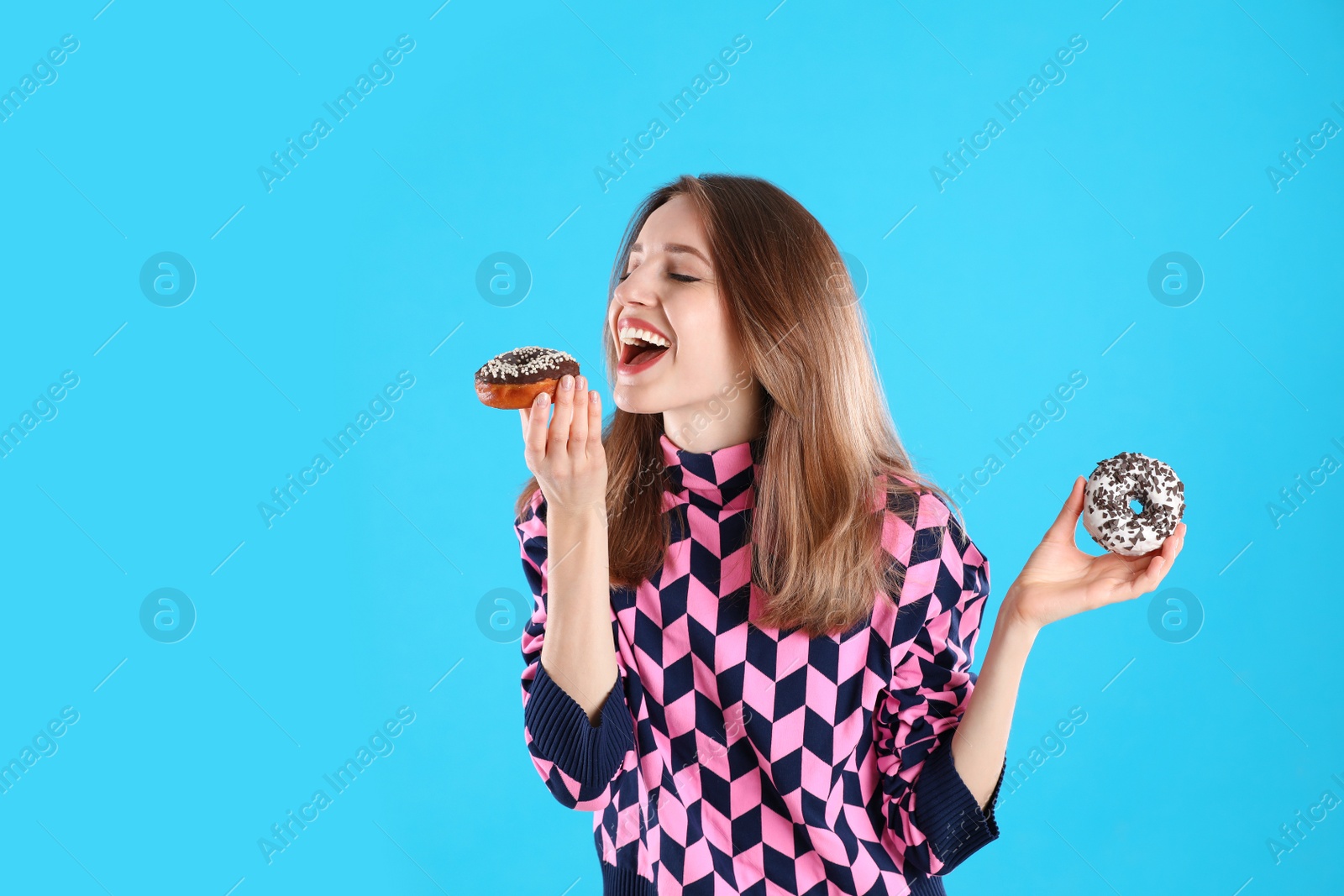 Photo of Beautiful young woman with donuts on light blue background