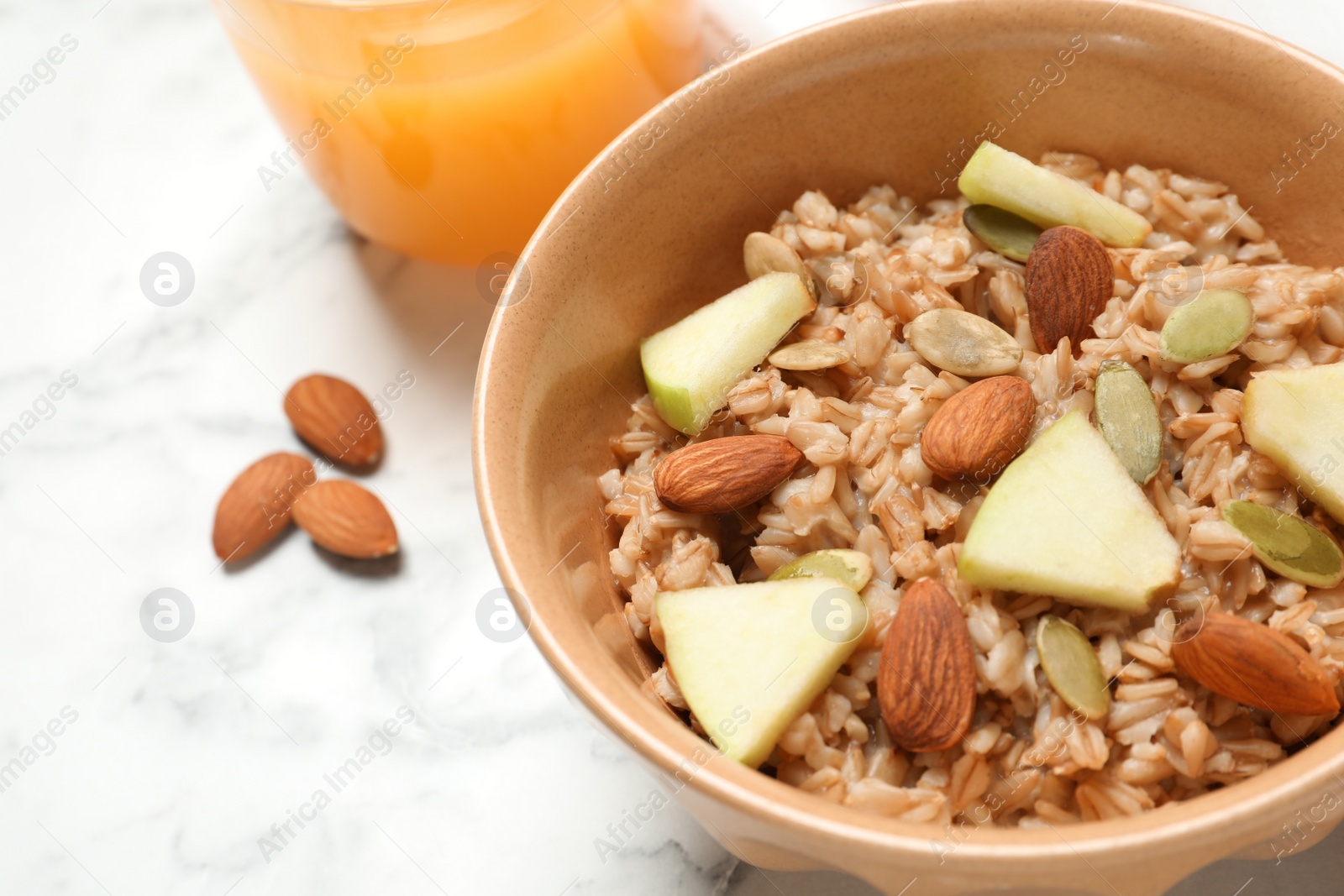 Photo of Tasty oatmeal with apples and almonds on light table, closeup. Healthy breakfast