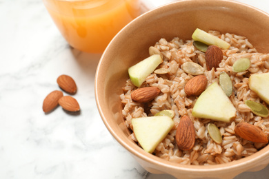 Tasty oatmeal with apples and almonds on light table, closeup. Healthy breakfast