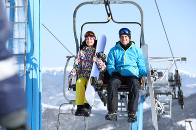 People using chairlift at mountain ski resort. Winter vacation