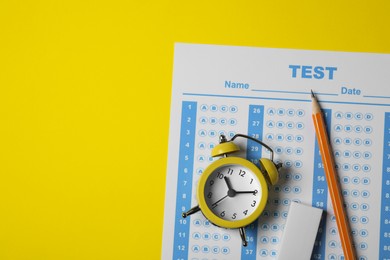 Photo of Answer sheet, pencil and alarm clock on yellow background, flat lay with space for text. Student passing exam