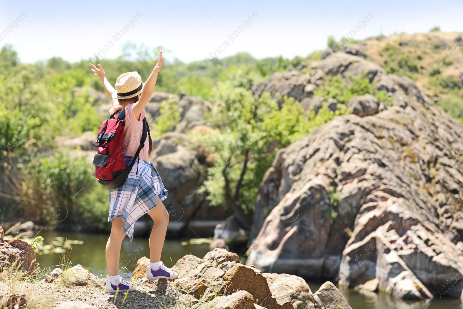 Photo of Little girl on rock near river. Summer camp