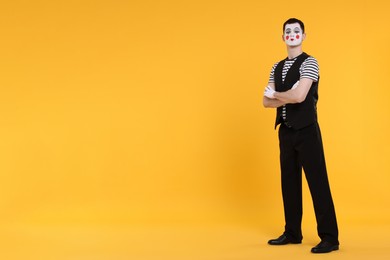 Funny mime artist posing on orange background. Space for text