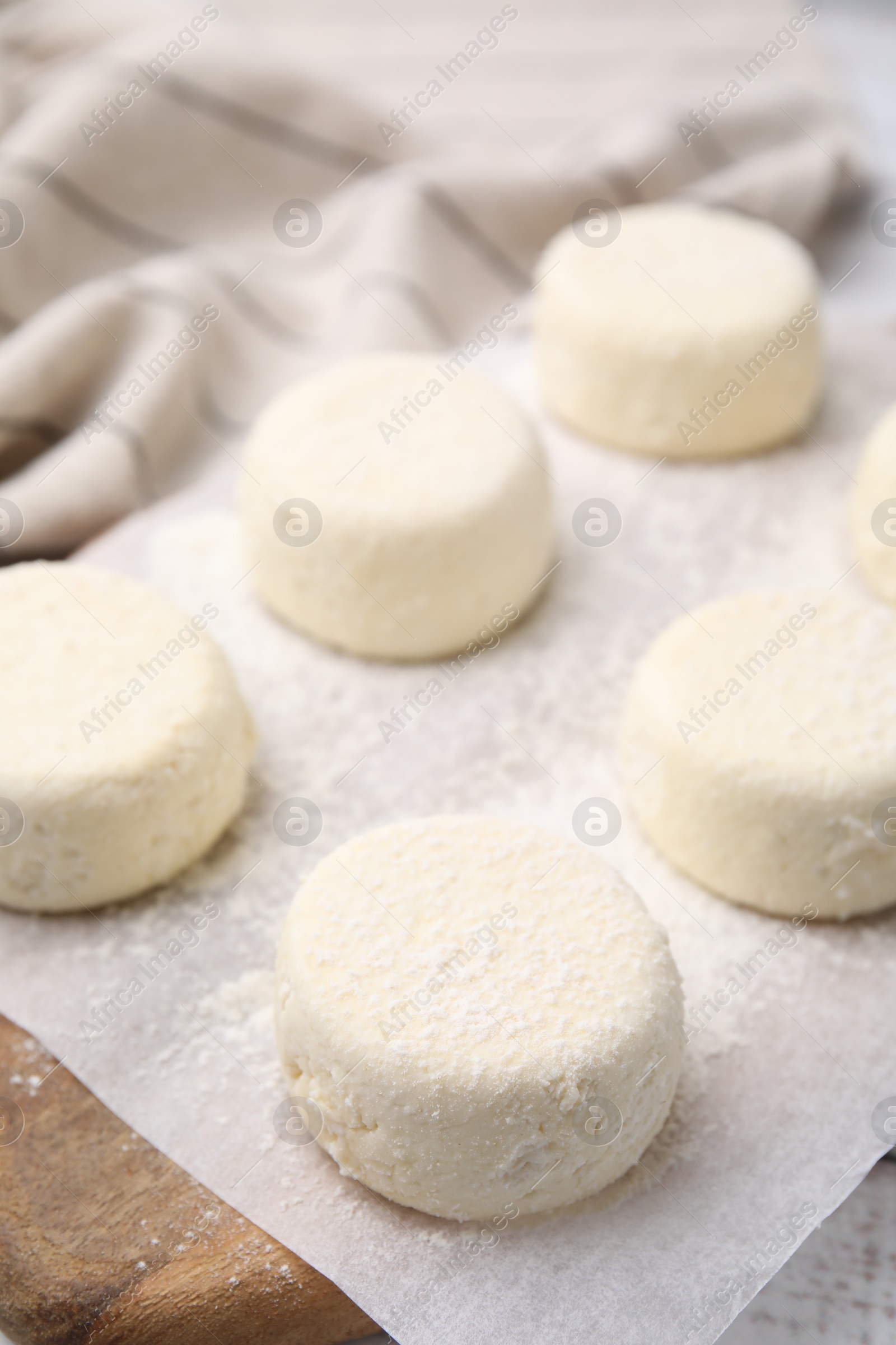 Photo of Uncooked cottage cheese pancakes on wooden board