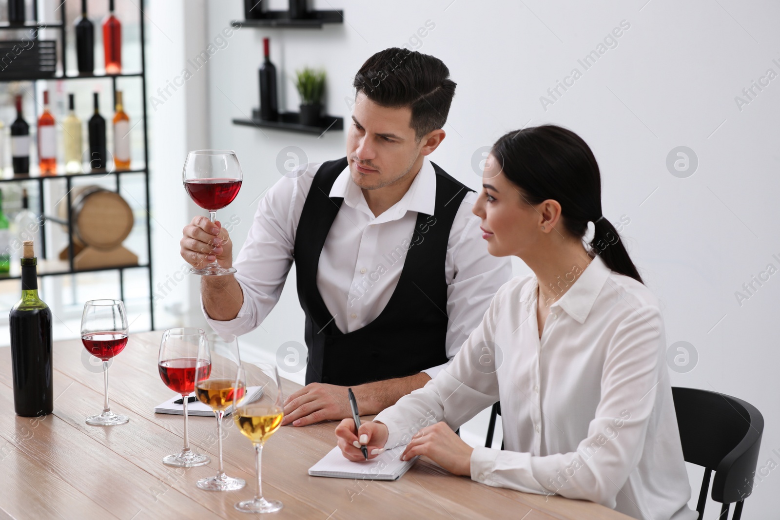 Photo of Sommeliers tasting different sorts of wine at table indoors