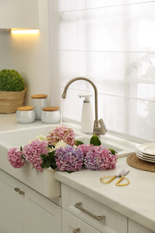 Photo of Bouquet with beautiful hydrangea flowers in sink