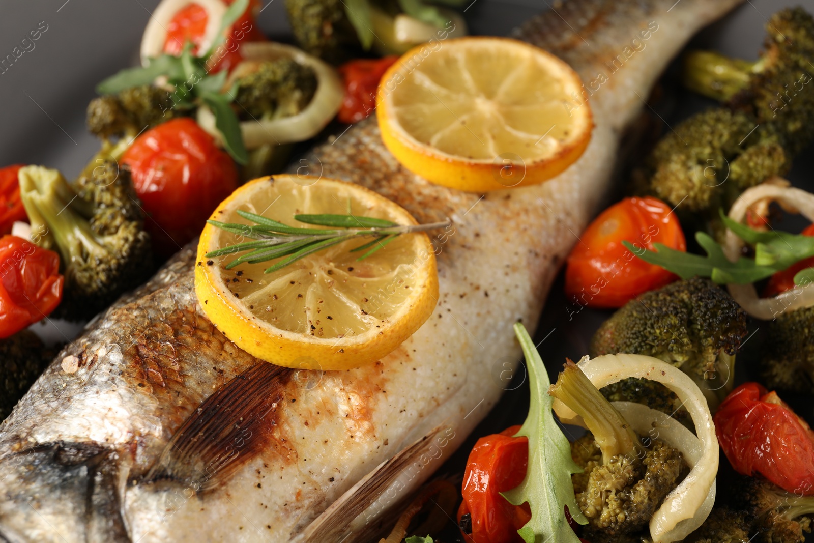 Photo of Baked fish with vegetables, rosemary and lemon, closeup