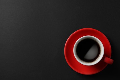 Photo of Cup with aromatic coffee on black background, top view. Space for text