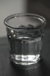 Glass of pure water on black table against blurred background, closeup