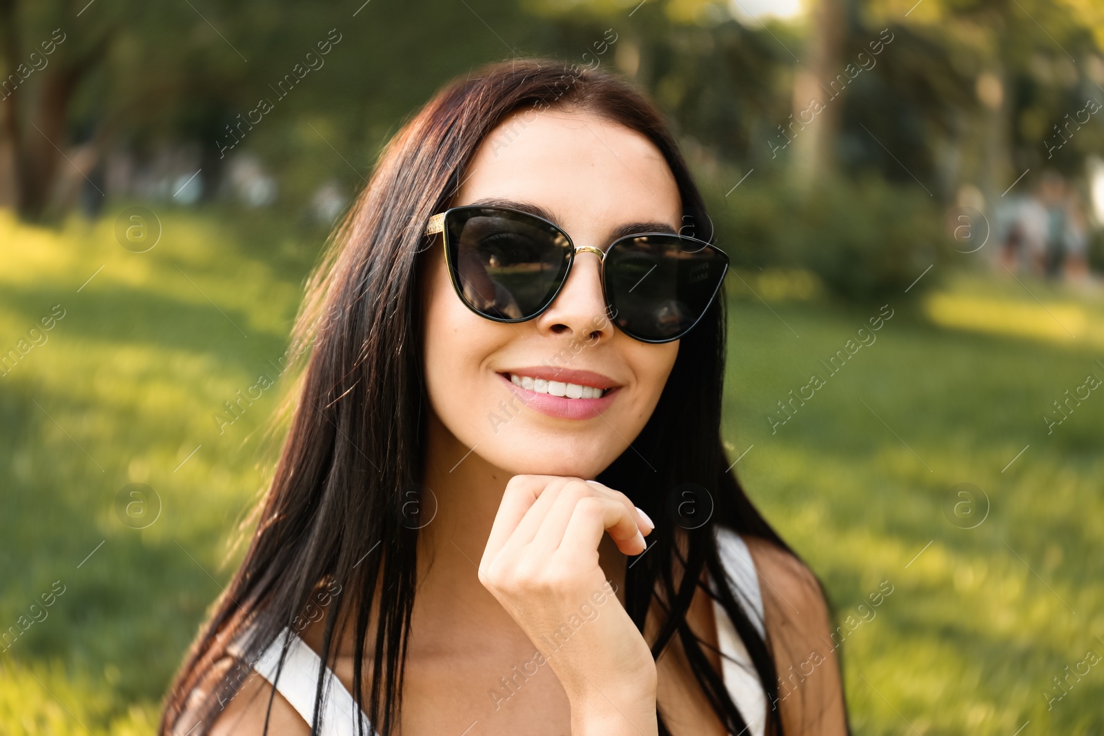 Photo of Beautiful young woman wearing stylish sunglasses in park