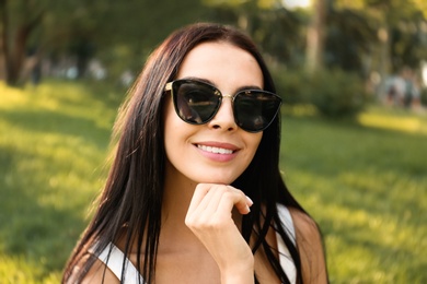 Beautiful young woman wearing stylish sunglasses in park