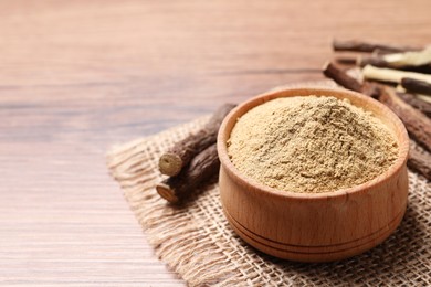 Photo of Dried sticks of liquorice root and powder on wooden table, closeup. Space for text