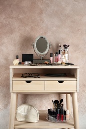 Dressing table with beauty accessories near color wall in room