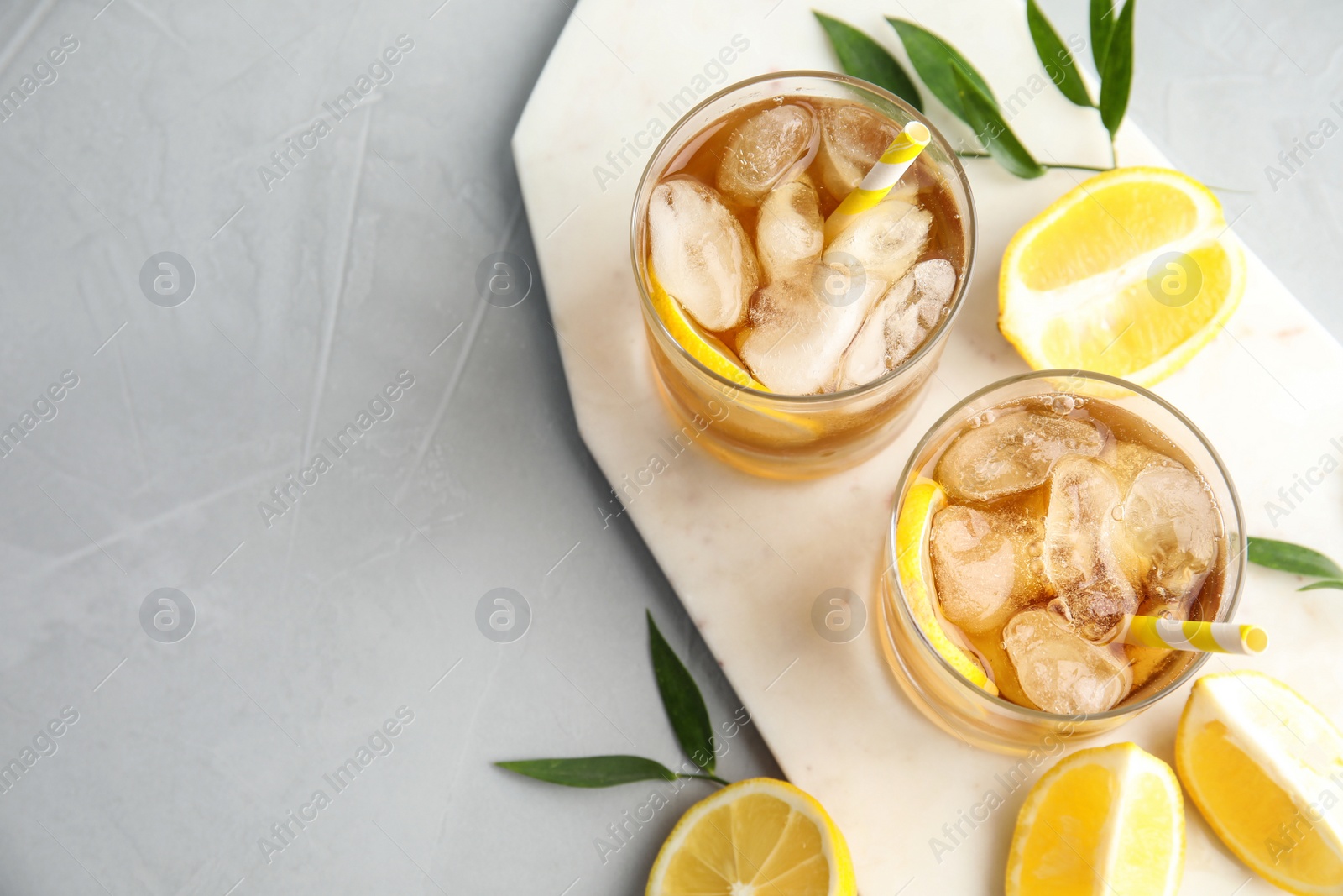 Photo of Glasses of lemonade with ice cubes and fruit on grey table, top view. Space for text