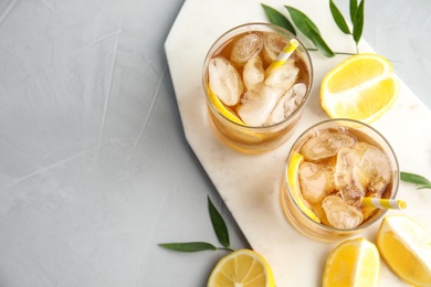 Glasses of lemonade with ice cubes and fruit on grey table, top view. Space for text